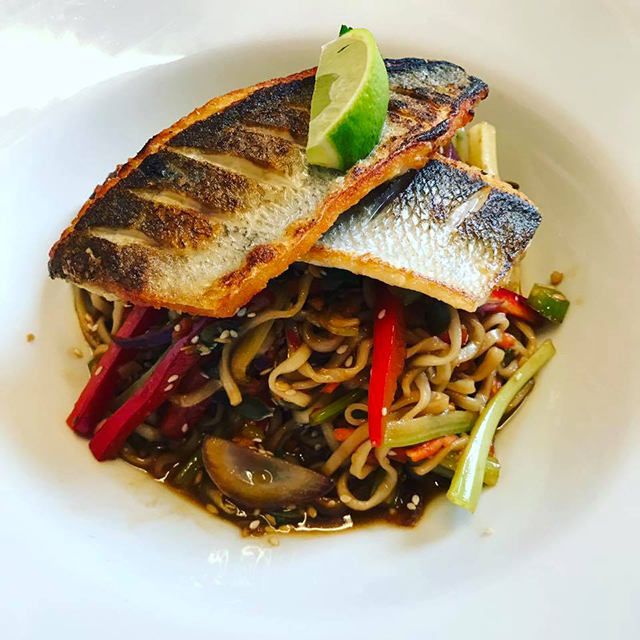 fish and noodles presented on a white china plate