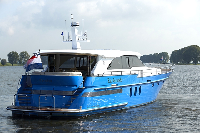 A motor yacht with a blue hull flying a French flag