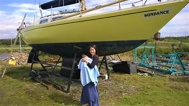 A mother and child next to a yellow yacht